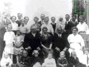 Foto de uma família, em destaque a de uma criança loira que aparece no canto superior direito da foto