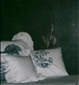 Foto de quarto escuro com um vulto próximo a cama